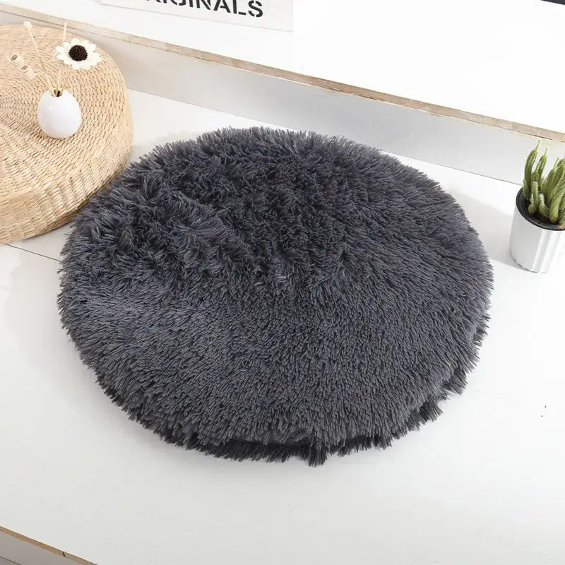 Lit rond pour petits animaux, tapis en peau de mouton gris sur table blanche