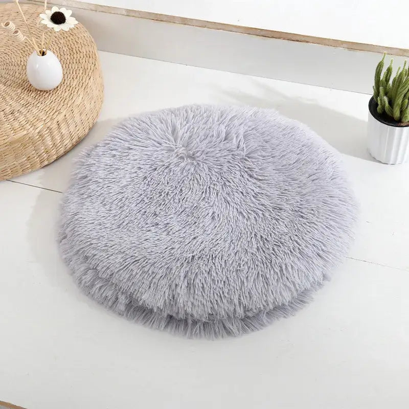 Lit rond en peau de mouton grise sur table blanche pour petits chats et chiens